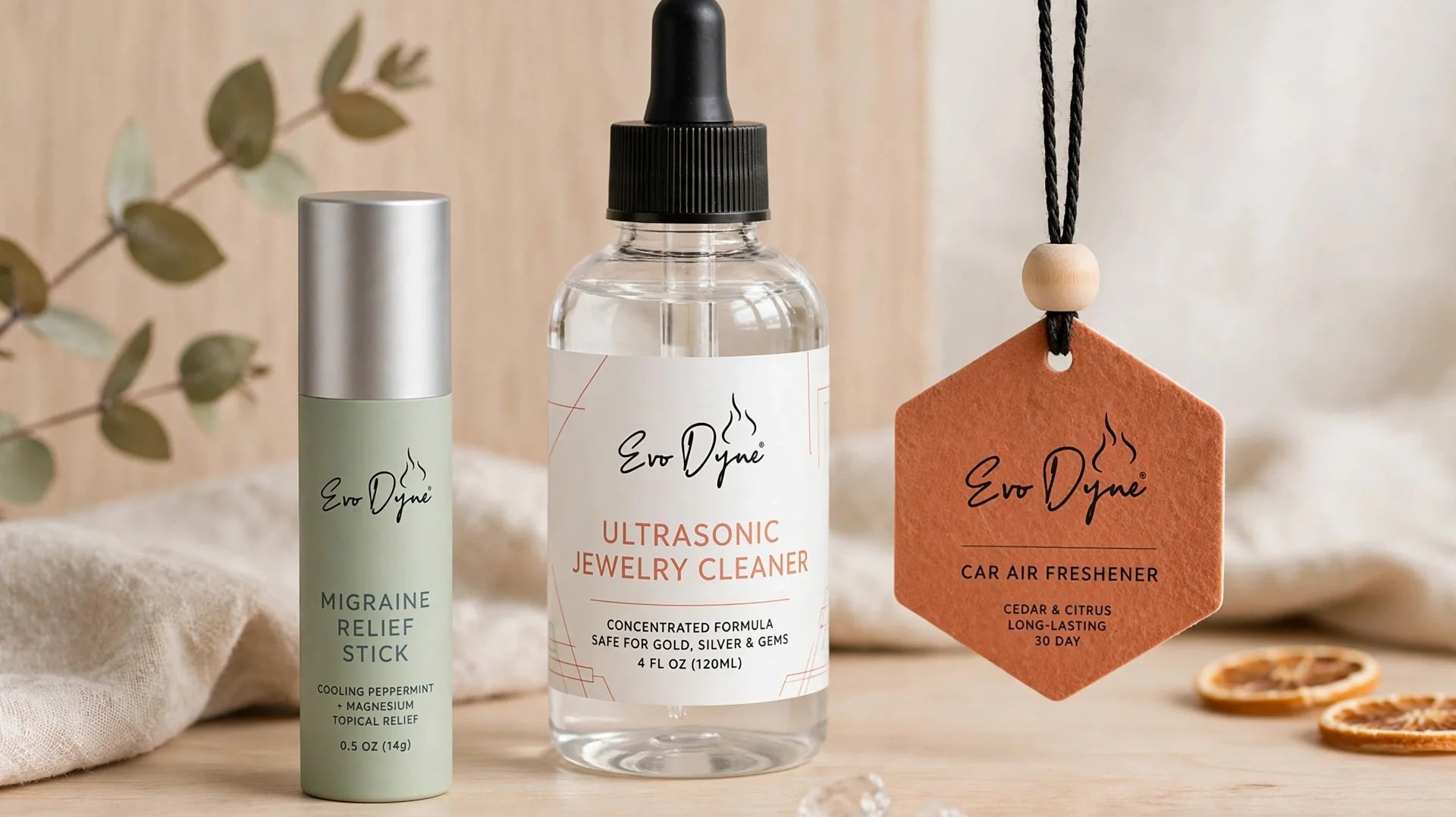 Evo Dyne products including a relief stick, jewelry cleaner, and car freshener arranged artfully on a wooden surface.