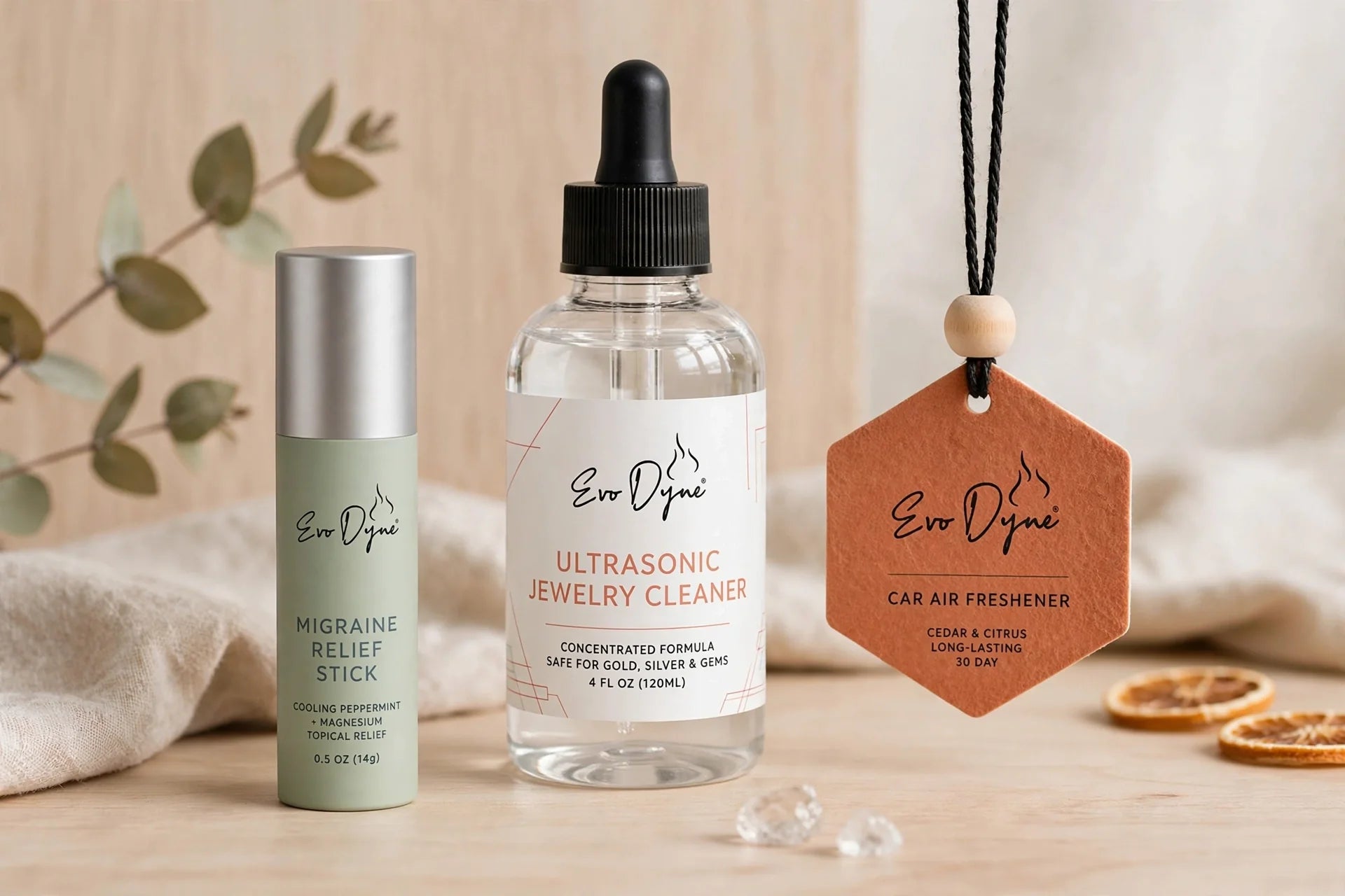 Evo Dyne products including a relief stick, jewelry cleaner, and car freshener arranged artfully on a wooden surface.