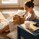 Woman grooming an orange cat beside Evo Dyne Styptic Powder jar and pet nail clippers
